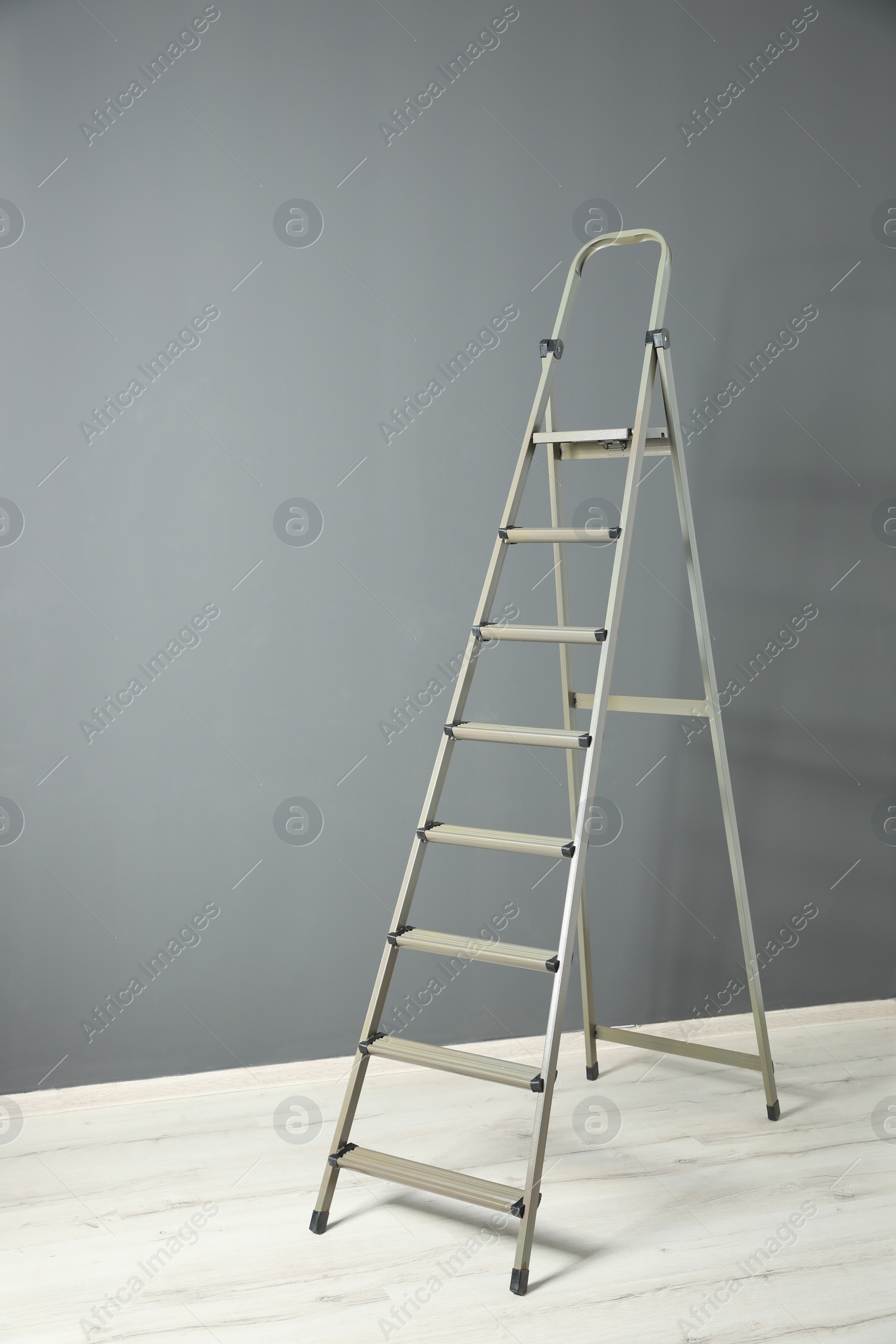 Photo of Modern metal step ladder near grey wall