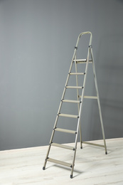 Modern metal step ladder near grey wall