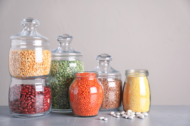 Photo of Jars with different cereals on grey table