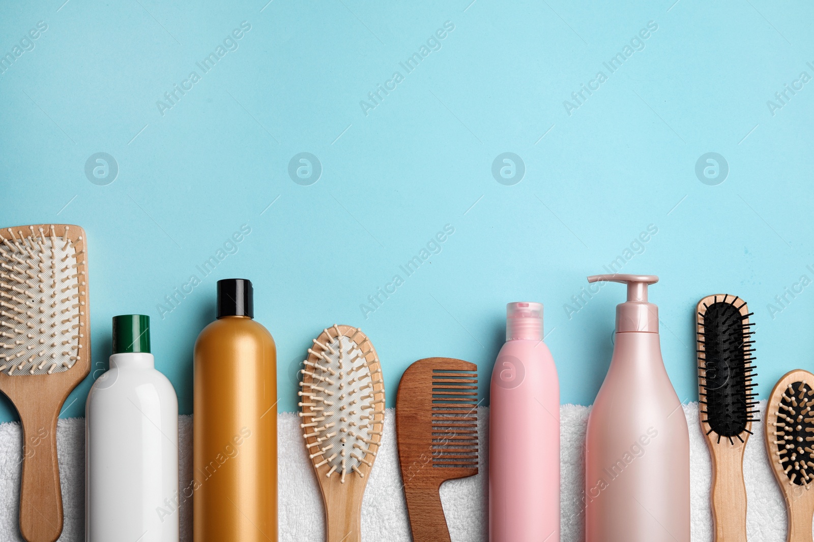 Photo of Flat lay composition with hair cosmetic products and tools on blue background. Space for text