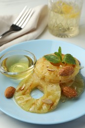 Photo of Tasty grilled pineapple slices served with mint and almonds on white table, closeup