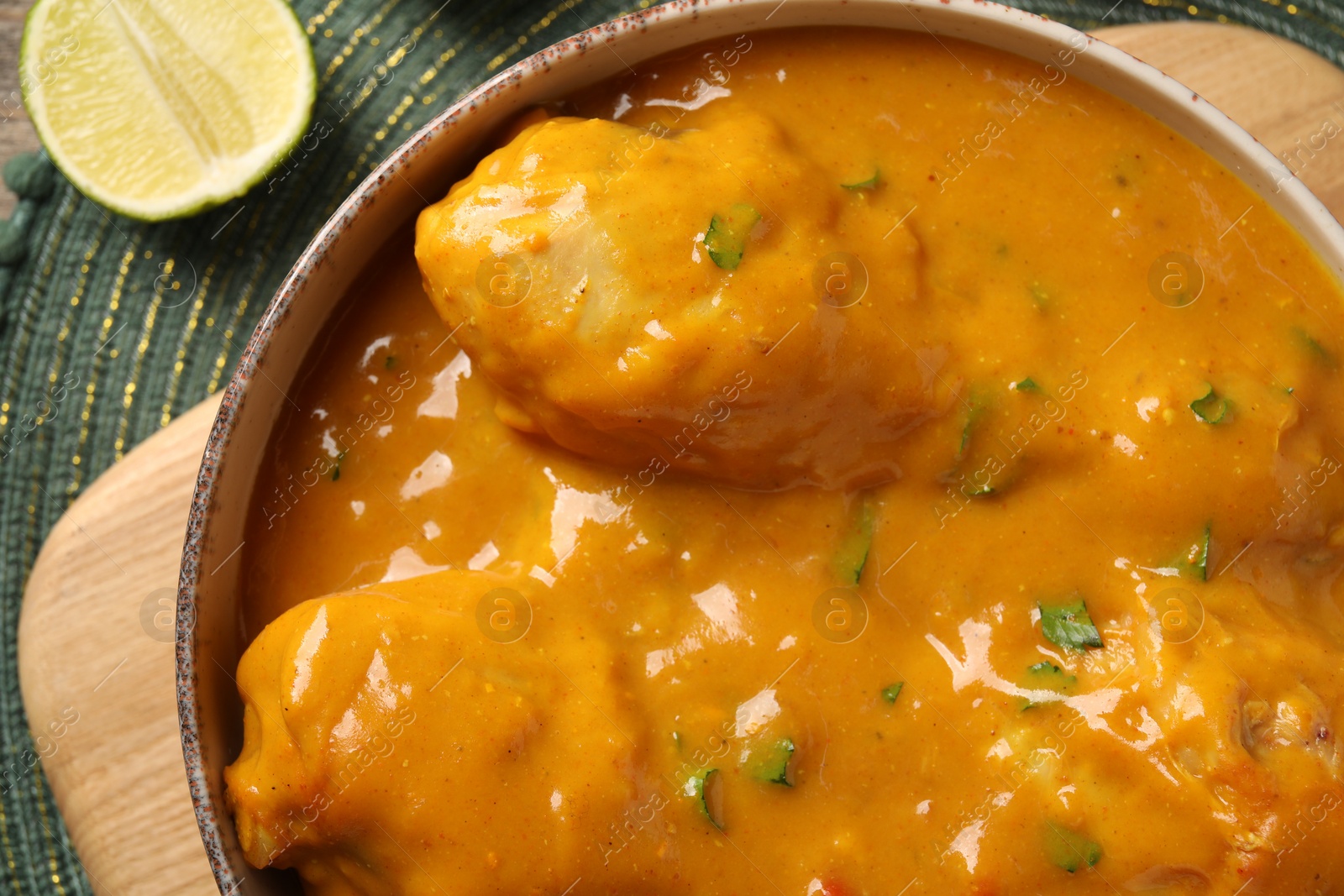 Photo of Tasty chicken curry and lime on green place mat, flat lay