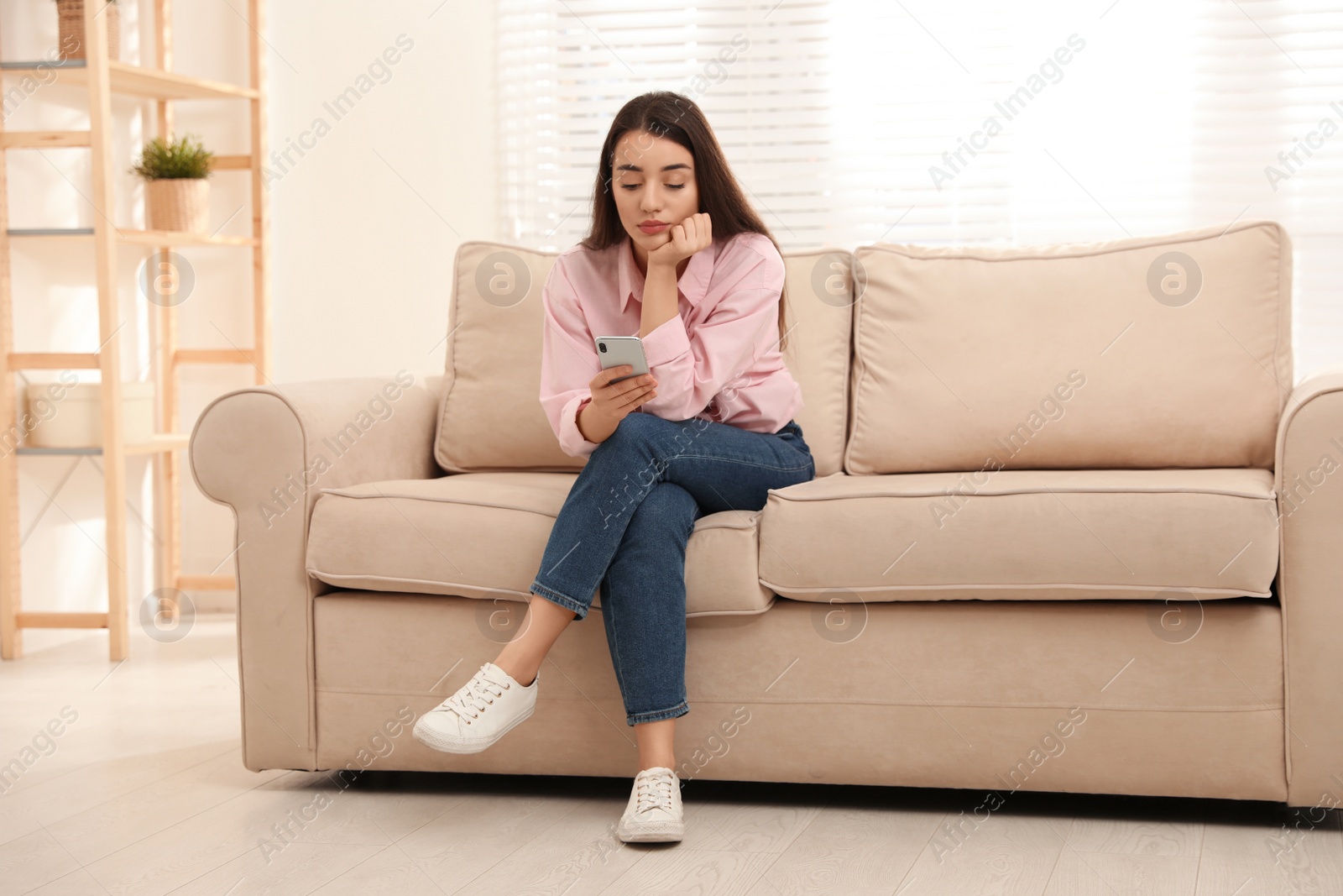 Photo of Young woman addicted to smartphone at home