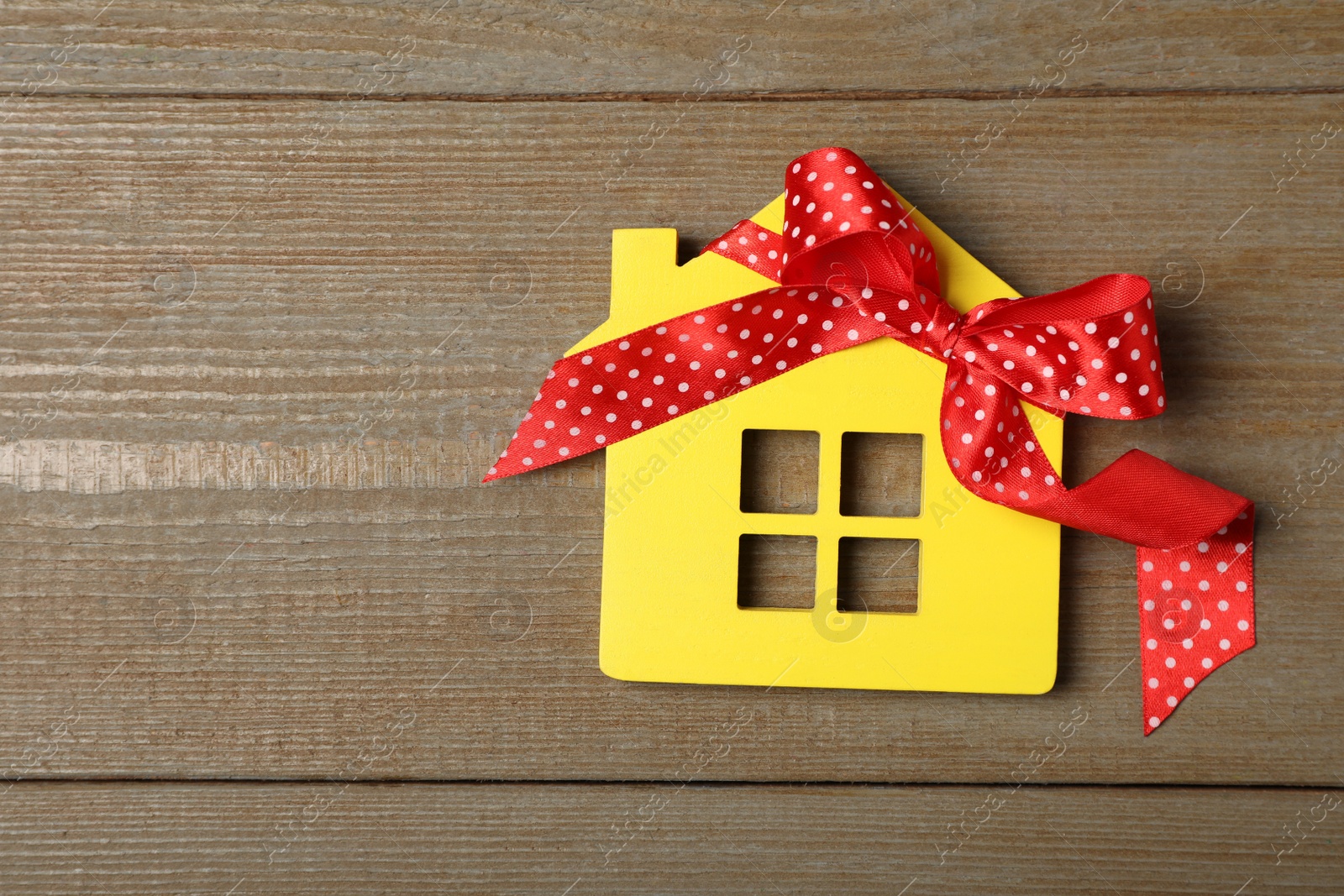 Photo of Yellow house model with bow on wooden table, top view and space for text. Housewarming party