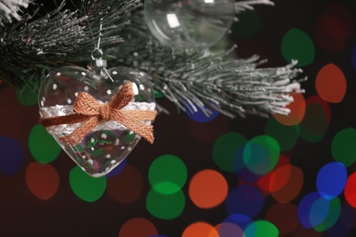 Photo of Heart shaped holiday bauble hanging on Christmas tree against blurred festive lights, closeup. Space for text