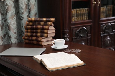Photo of Laptop, books and cupcoffee on wooden table in library reading room