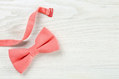 Stylish pink bow tie on white wooden background, top view. Space for text