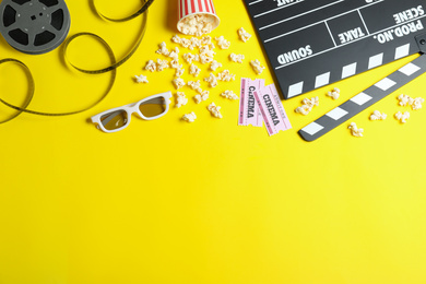 Photo of Flat lay composition with cinema tickets and clapperboard on yellow background, space for text