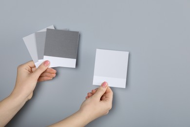 Photo of Woman with color sample cards choosing paint shade near grey wall, closeup. Interior design