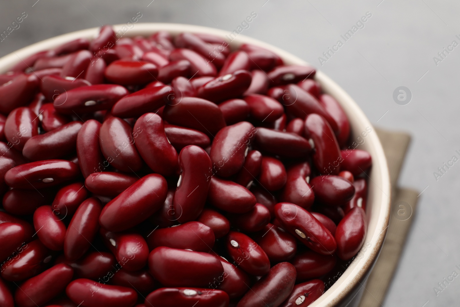 Photo of Raw red kidney beans in bowl on table, closeup