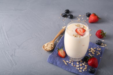 Photo of Tasty yogurt in glass, oats and berries on grey table, space for text