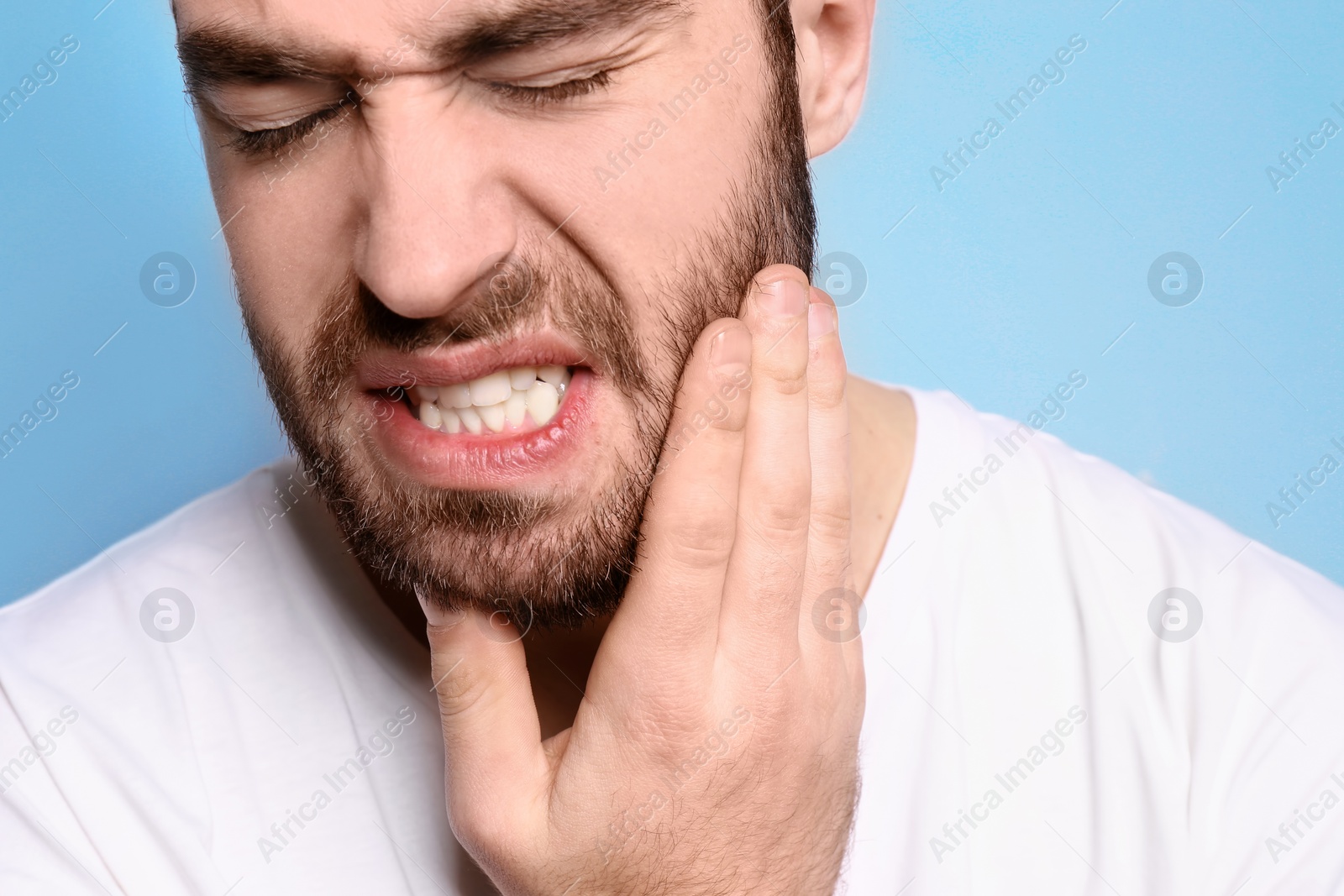 Photo of Young man suffering from toothache on grey background