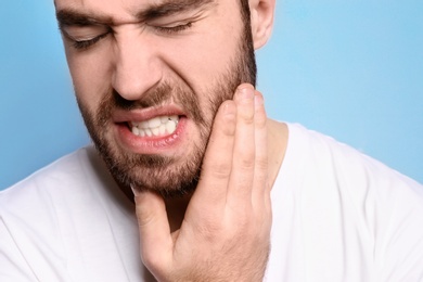 Young man suffering from toothache on grey background