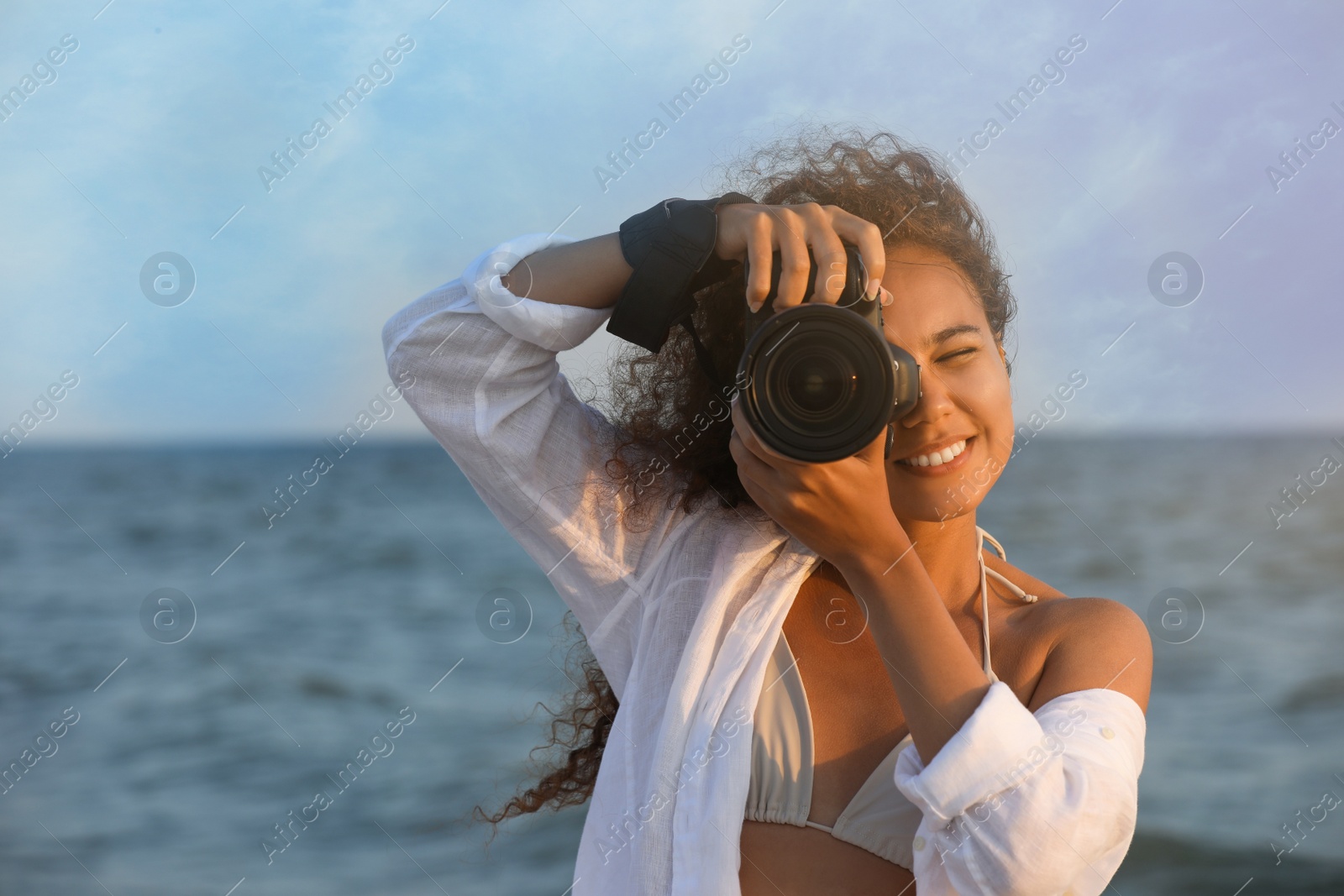 Photo of African American photographer taking photo with professional camera near sea