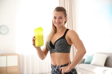 Young sporty woman with bottle of protein shake at home