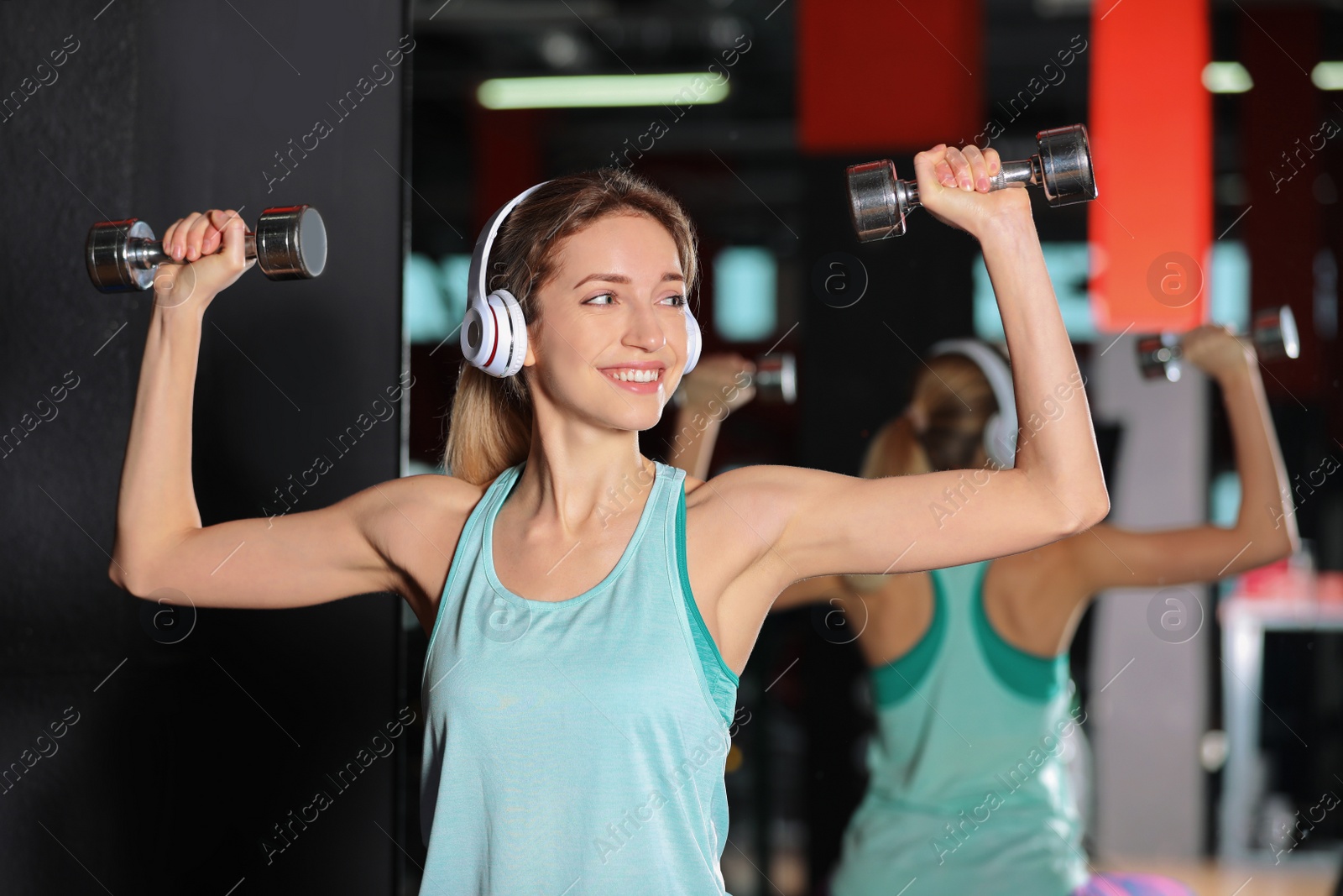Photo of Young woman with headphones listening to music and working out at gym