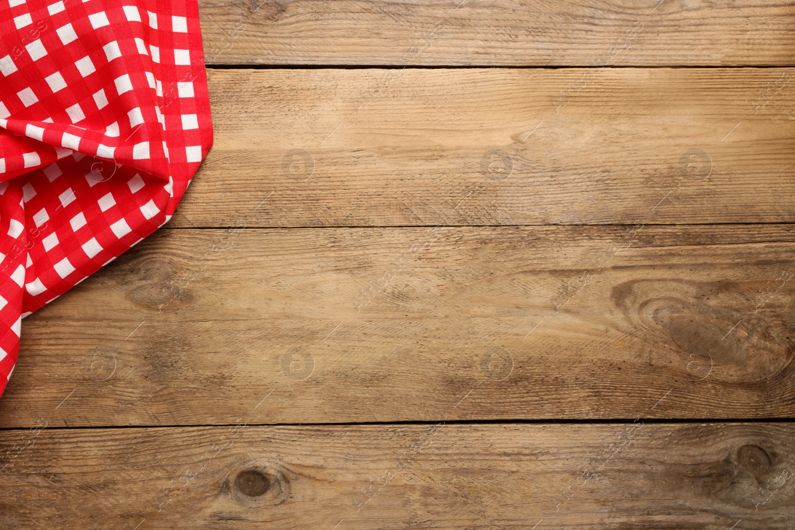 Photo of Checkered tablecloth on wooden table, top view. Space for text