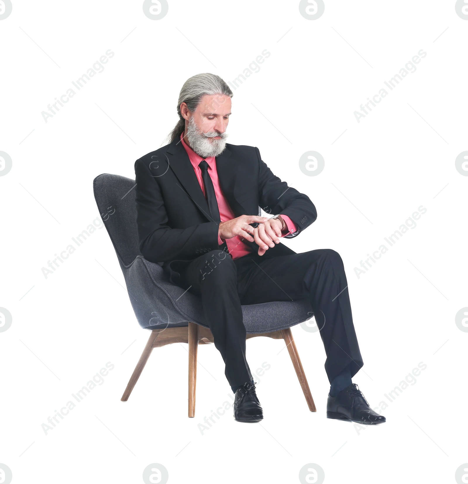 Photo of Handsome bearded mature man in suit sitting in armchair on white background