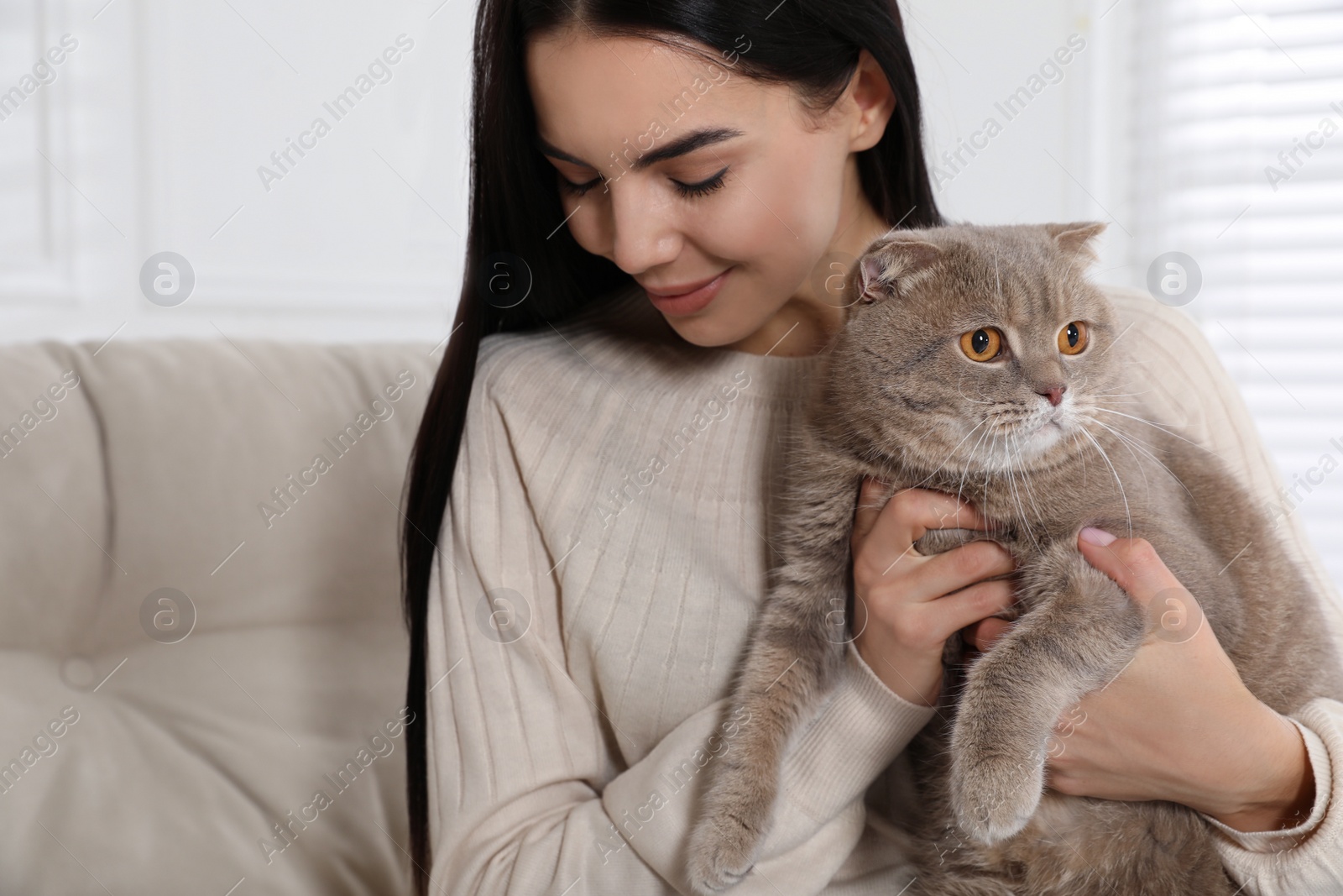 Photo of Woman with her adorable cat on sofa at home