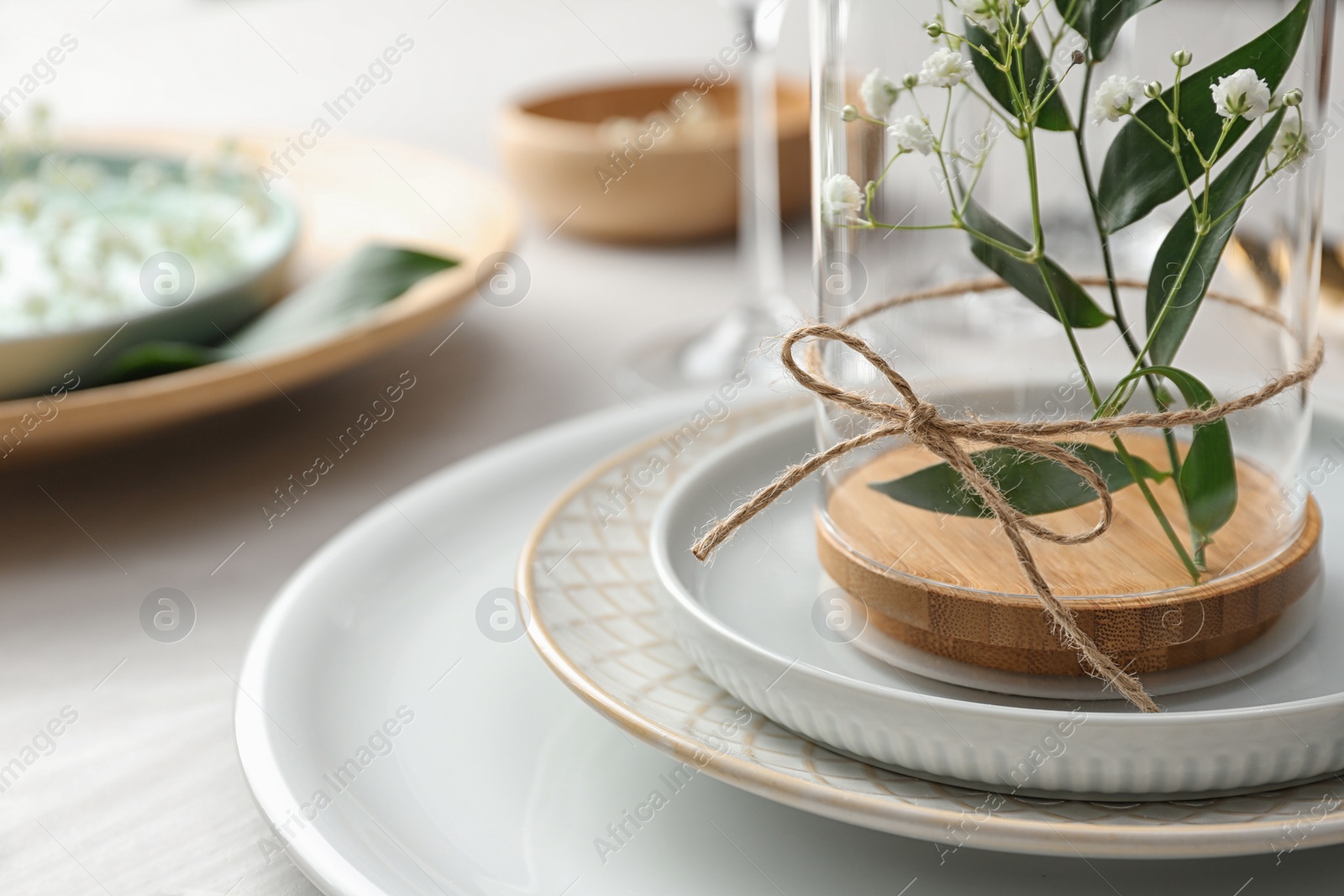 Photo of Glass with flowers on table, closeup. Festive setting