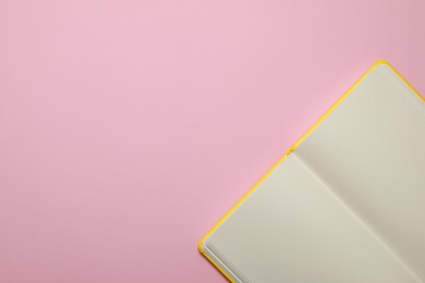 Blank notebook on pale pink background, top view. Space for text