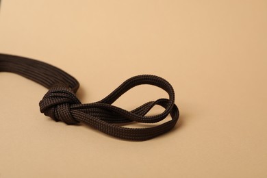 Photo of Dark brown shoe laces tied in knot on beige background