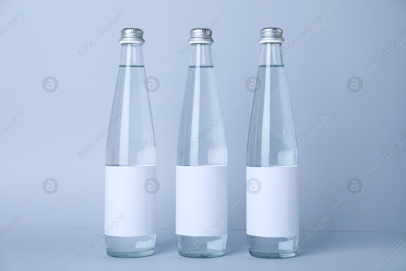Photo of Glass bottles with soda water on light background