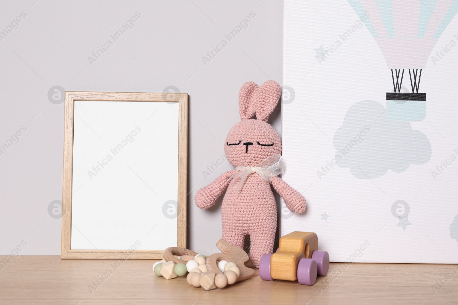 Photo of Empty square frame, picture and different toys on wooden table