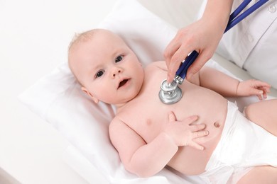 Photo of Pediatrician examining cute little baby with stethoscope in clinic, above view