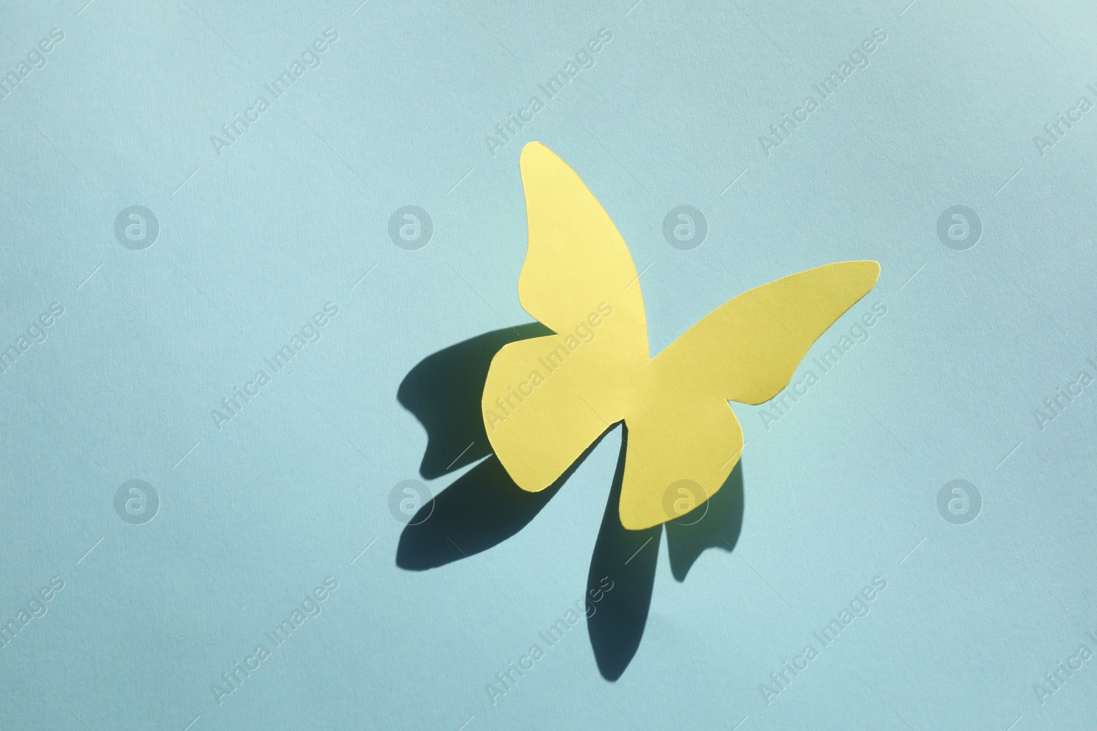 Photo of Yellow paper butterfly on turquoise background, top view