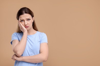 Photo of Portrait of sad woman on beige background, space for text