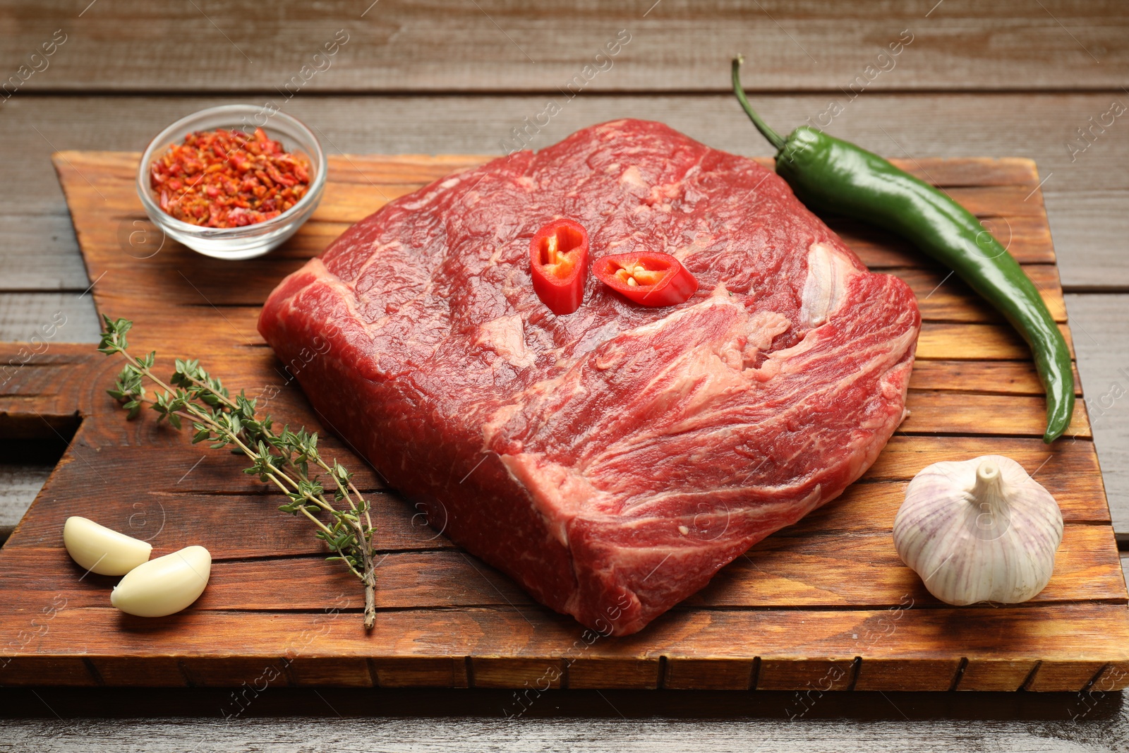 Photo of Fresh raw beef cut with spices on wooden table