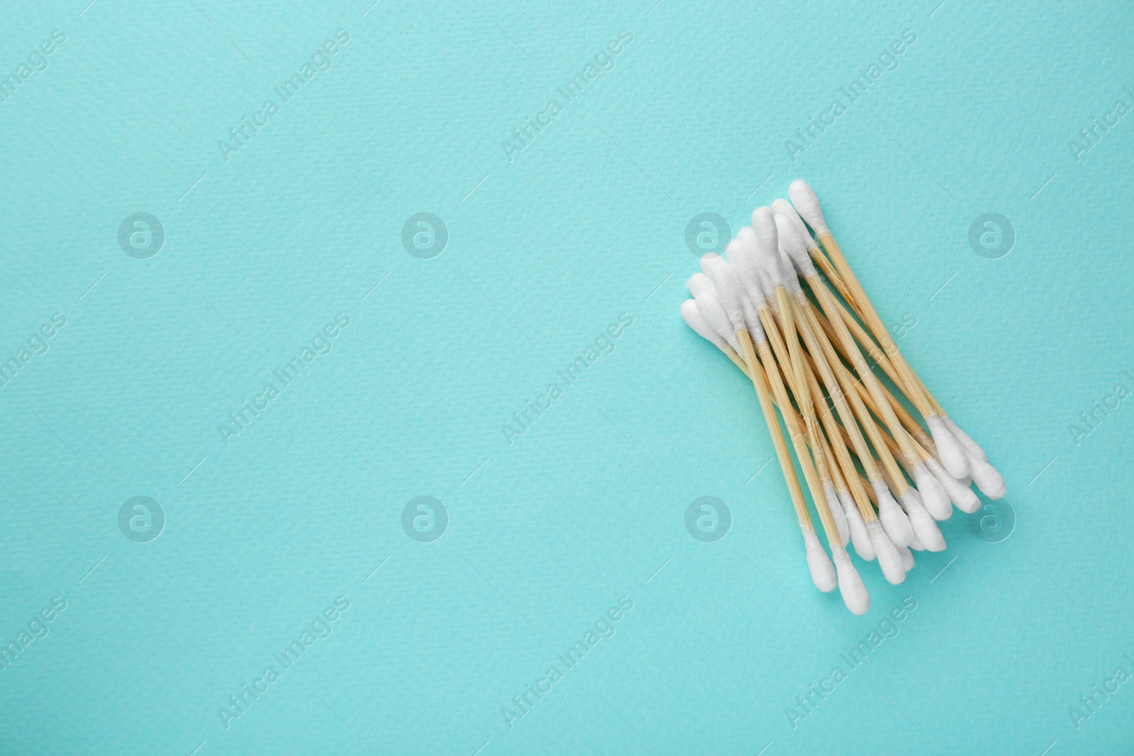 Photo of Many wooden cotton buds on turquoise background, flat lay. Space for text