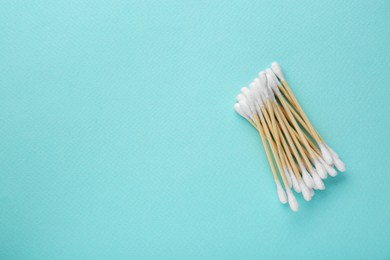 Photo of Many wooden cotton buds on turquoise background, flat lay. Space for text