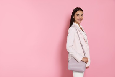 Beautiful young woman with stylish bag on pink background, space for text