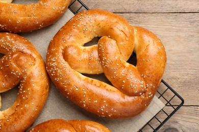 Photo of Cooling rack with delicious freshly baked pretzels on wooden table, top view