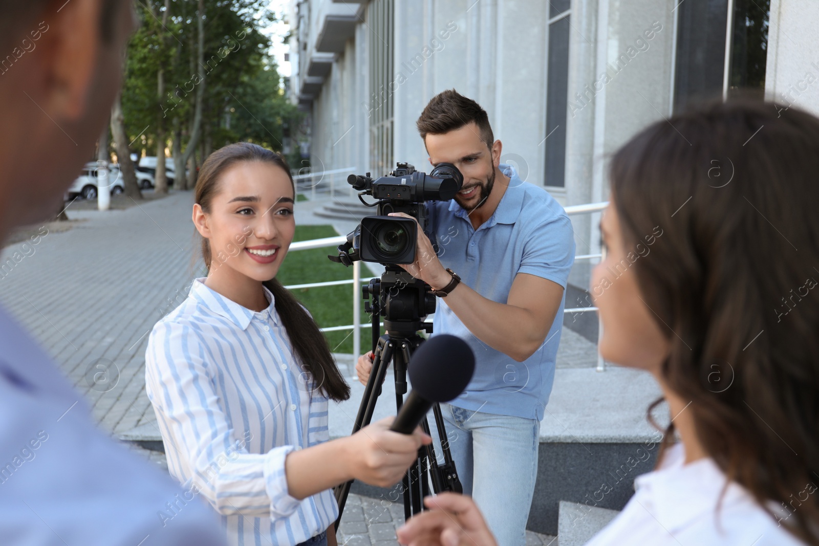 Photo of Professional journalist and operator with video camera taking interview outdoors