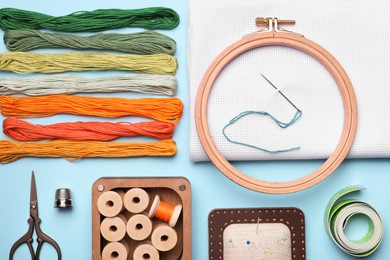 Photo of Flat lay composition with embroidery accessories on light blue background