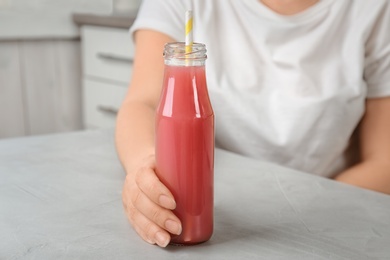 Photo of Woman with bottle of tasty juice at table