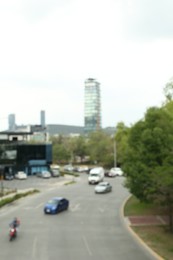 Photo of Modern cars on road near trees and building, blurred view