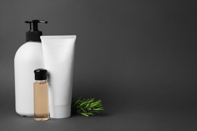 Cosmetic products and rosemary on dark grey background. Space for text