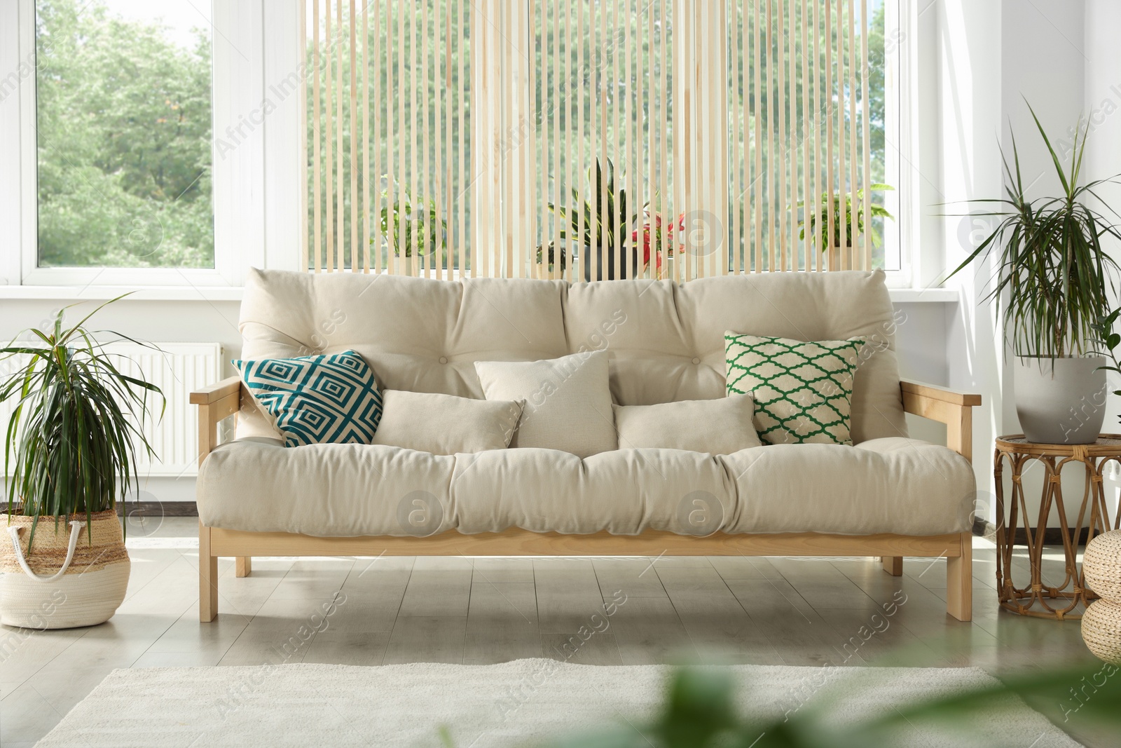 Photo of Stylish room interior with comfortable sofa and beautiful houseplants