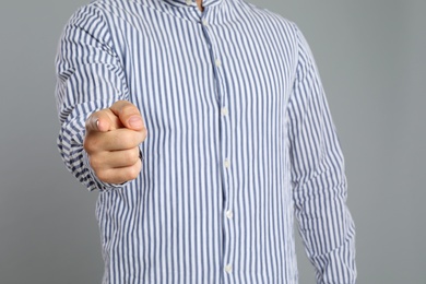 Photo of Man touching something on grey background, closeup. Finger gesture