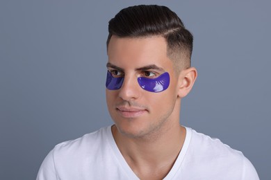 Man with blue under eye patches on grey background