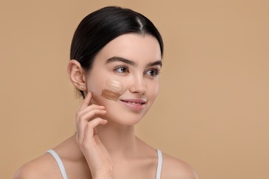 Photo of Teenage girl with swatches of foundation on face against beige background. Space for text
