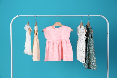 Rack with stylish child clothes on color background