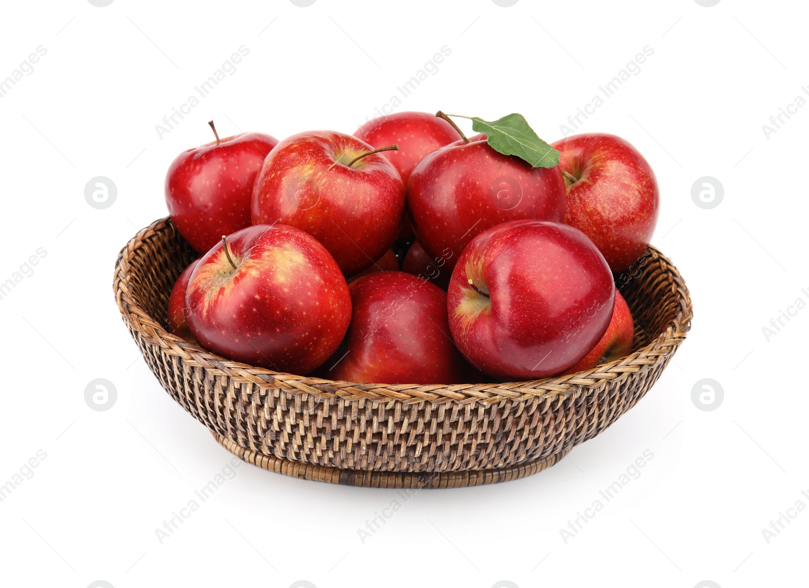 Photo of Wicker bowl of ripe juicy red apples with leaf on white background