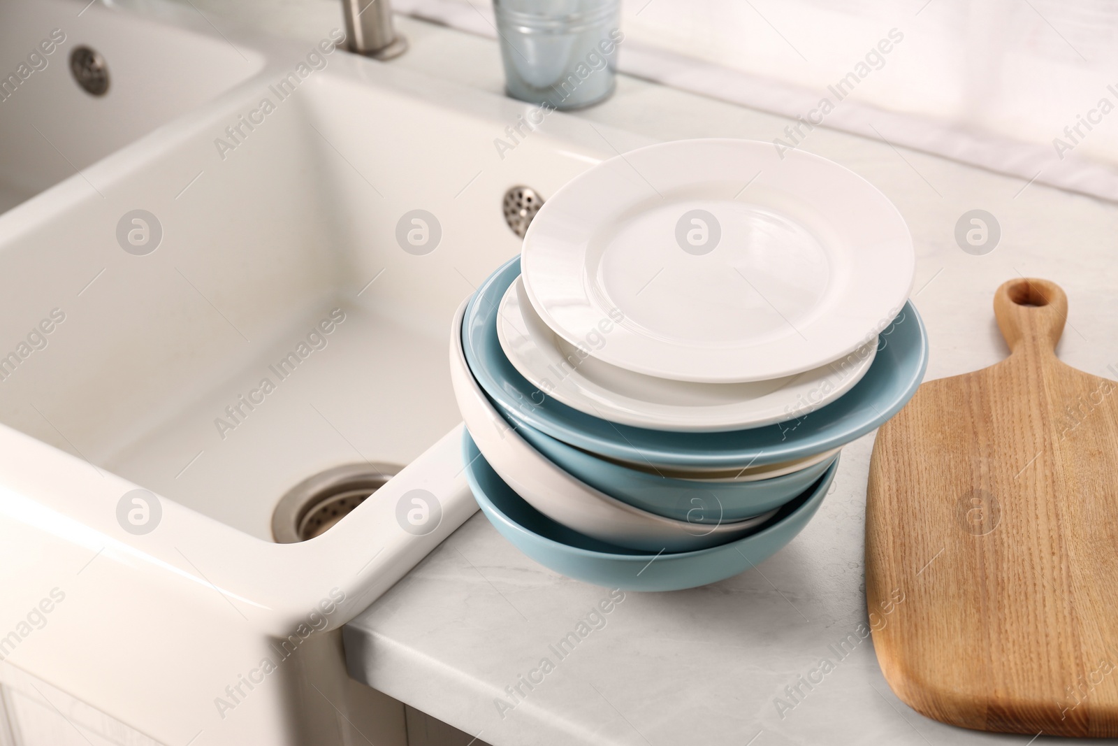 Photo of Clean tableware on light countertop near sink in kitchen