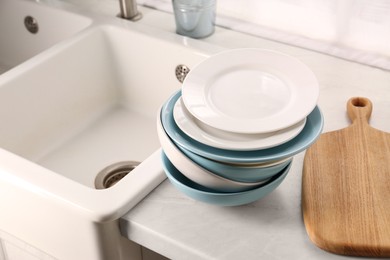 Photo of Clean tableware on light countertop near sink in kitchen
