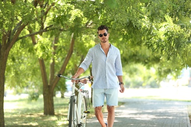 Photo of Handsome young hipster man with bicycle in park